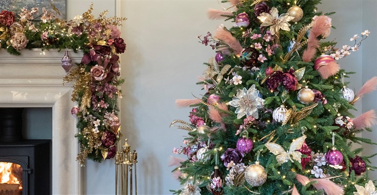 gold, pink and purple christmas decorations on artificial christmas tree and garland draped over fireplace