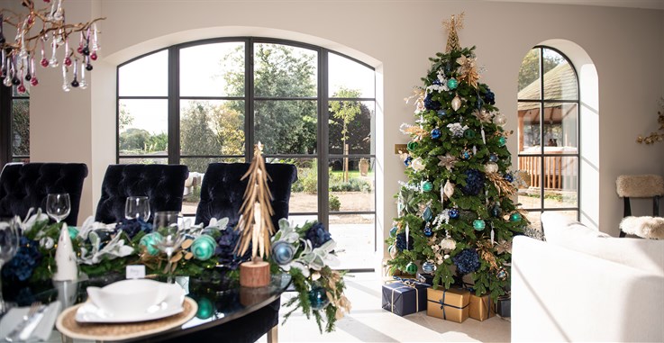 festive decorated table and christmas tree with blue, green and gold decorations