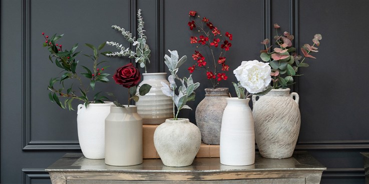 faux flowers and foliage stems in ceramic vases on a table
