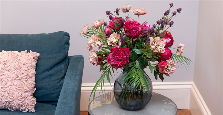 artificial pink and purple flower arrangement in glass vase