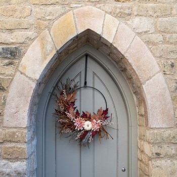 pumpkin and foliage wreath on door under archway