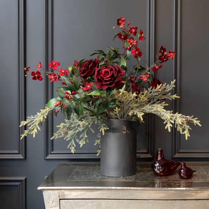 red faux flowers and foliage arranged in black churn vase