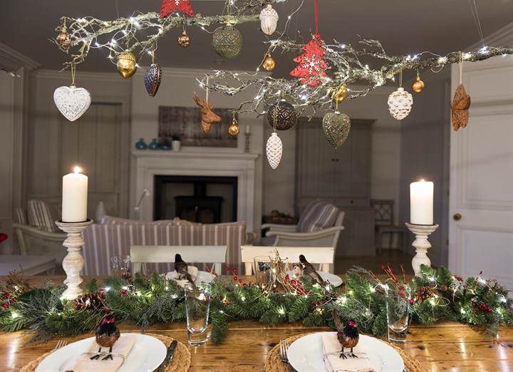 seasonal table display with garland, candles, decorative birds and overhead hanging decorations and baubles