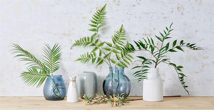 artificial foliage stems in ceramic and glass vases