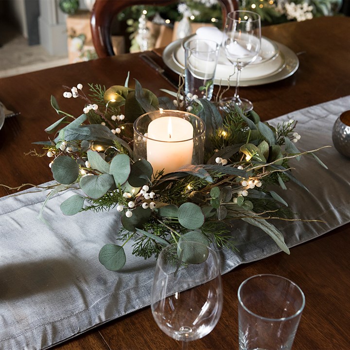 candle holder with foliage and berries on dining table