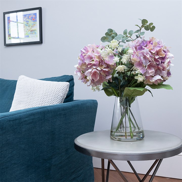 pink and green artificial flowers in vase in white living room