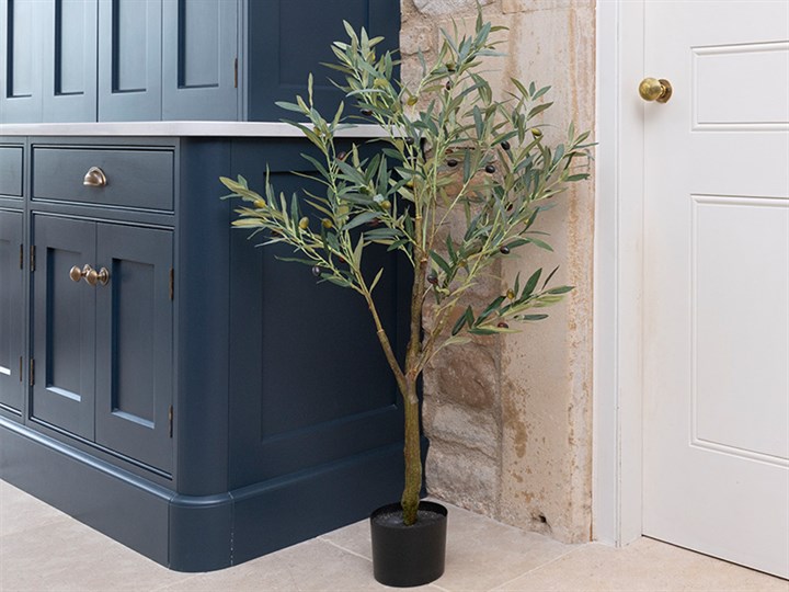 artificial small tree in plastic pot next to doorway and dresser