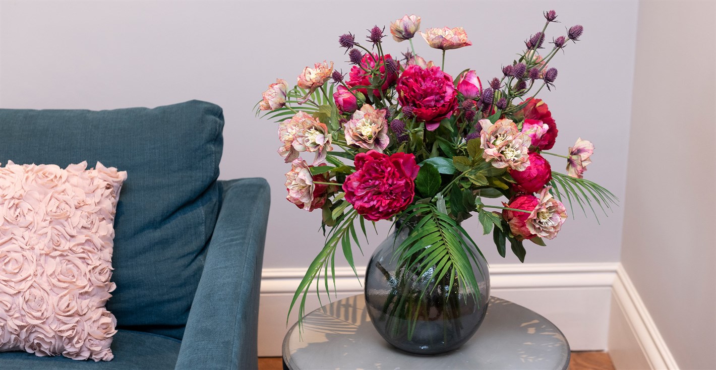artificial pink and purple flower arrangement in glass vase