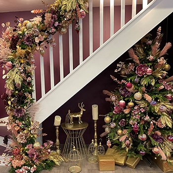 christmas display around staircase with garland running up the banister 