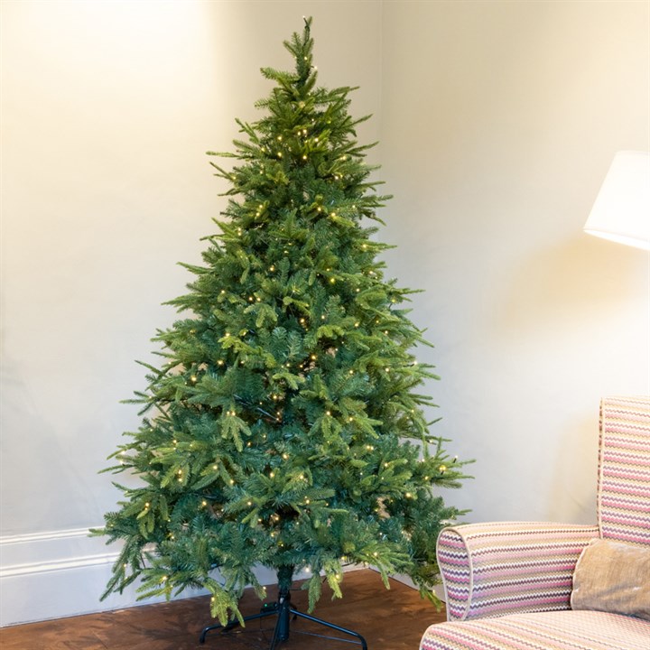christmas tree without decorations in corner of room next to armchair and lamp