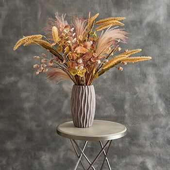 arrangement made of faux grasses in textured stone vase