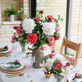 faux peonies and dahlias in vase on dining table