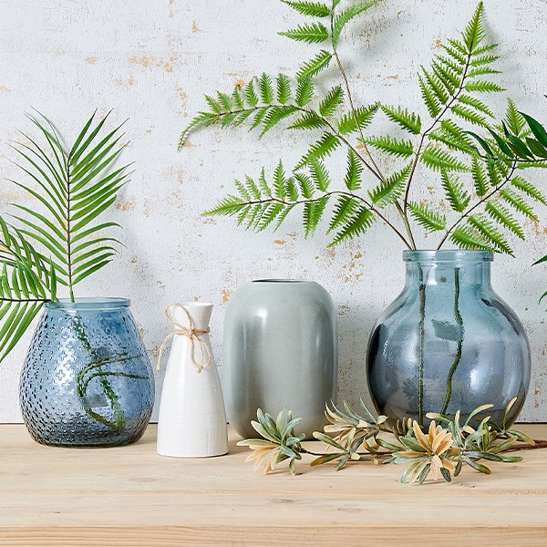 foliage stems in and around a range of glass and ceramic vases