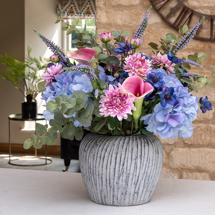 artificial floral arrangement in round stone vase