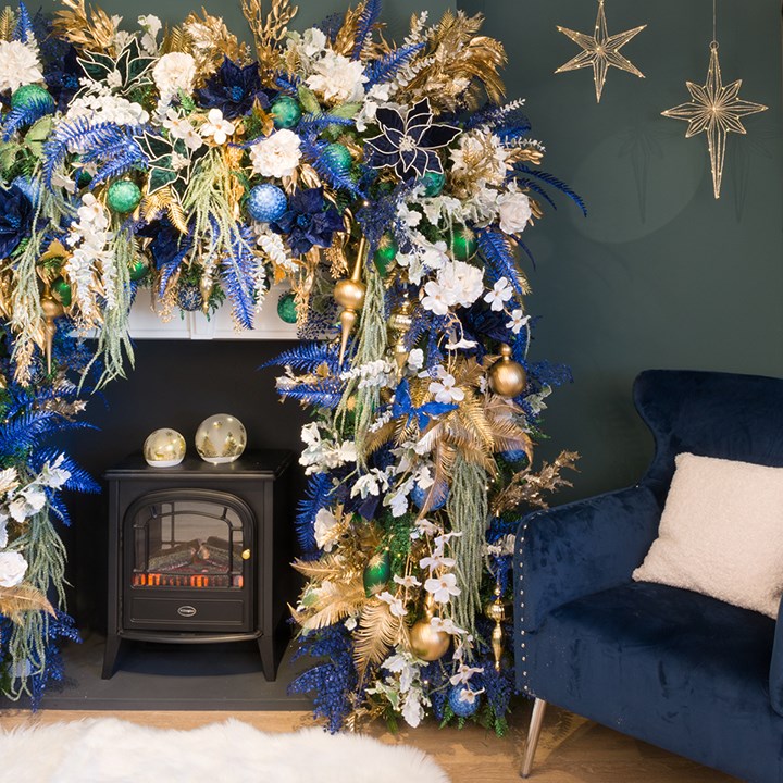 blue, gold and white christmas decorations in an arch over a fireplace