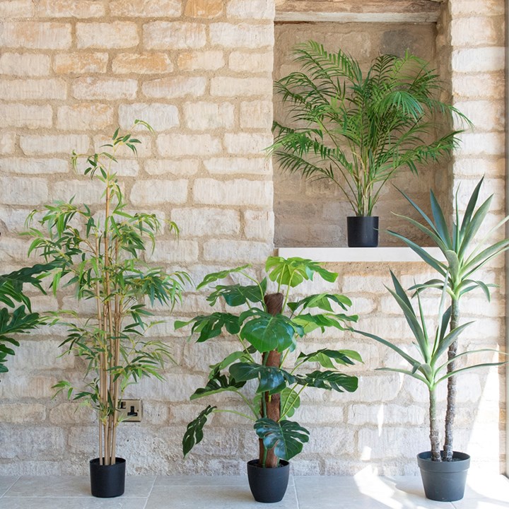 assortment of artificial plants and trees in front of a wall