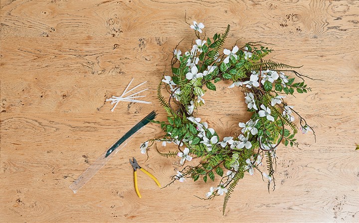 foliage and flower wreath with tools on table