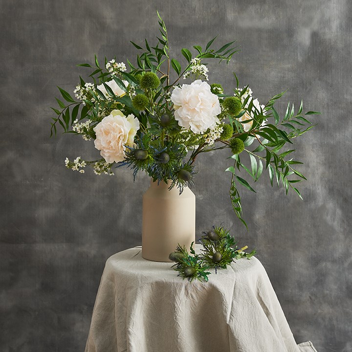 green and white artificial arrangement in stone vase