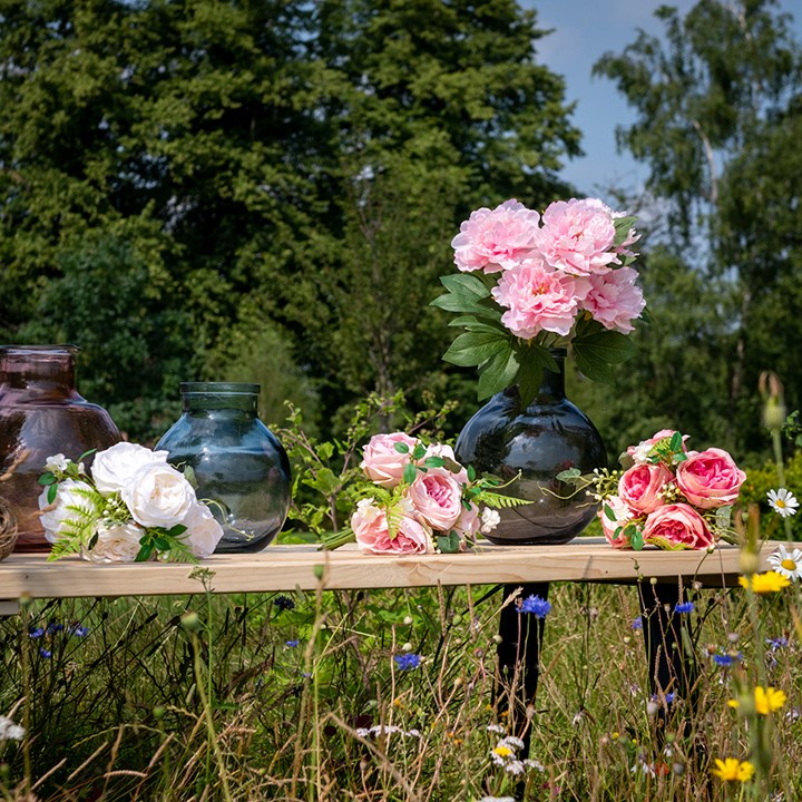 artificial bouquets and bunches on a bench with glass vases