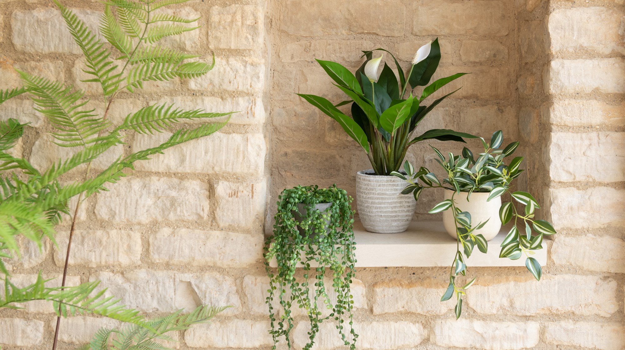 Beautiful potted faux plants on a brick background