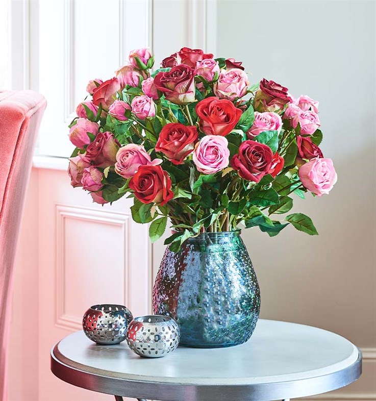 artificial pink and red roses in textured recycled glass vase