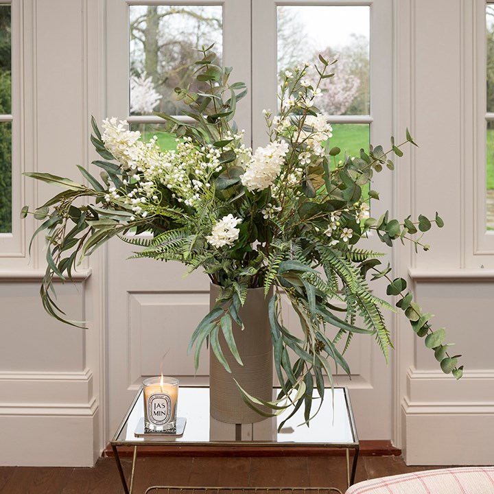 artificial foliage and lilac arrangement in ceramic vase