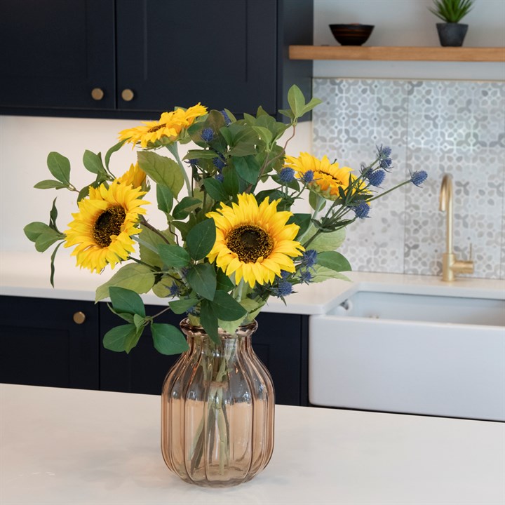 artificial sunflowers and foliage arrangement in glass vase