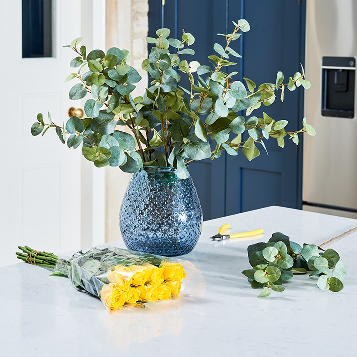 yellow artificial roses and eucalyptus in vase