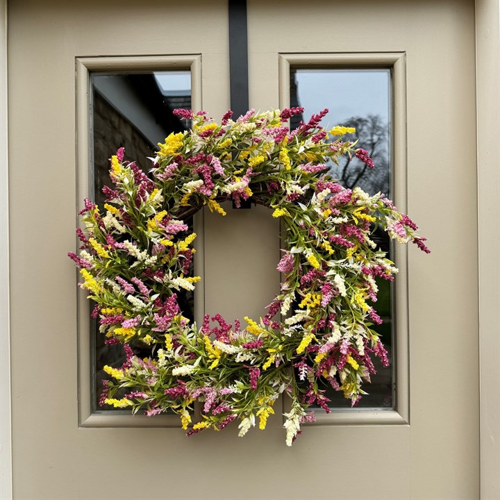 white, yellow and pink floral wreath hung on a wall