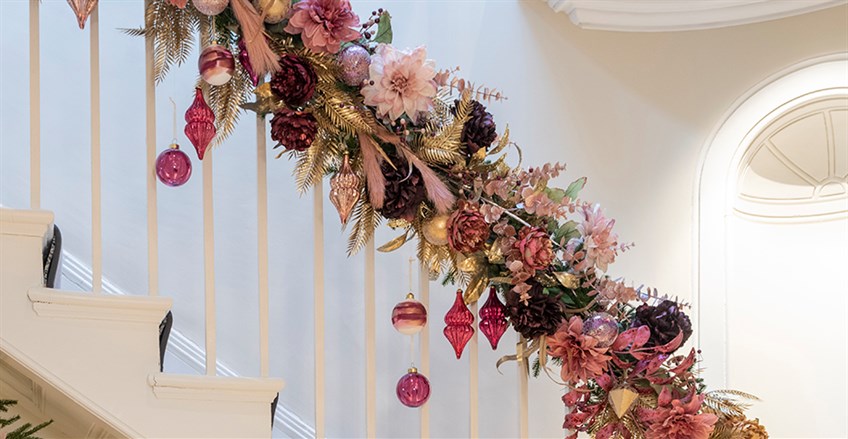 Christmas Garland on bannister of stairs, covered with pink and purple decorations