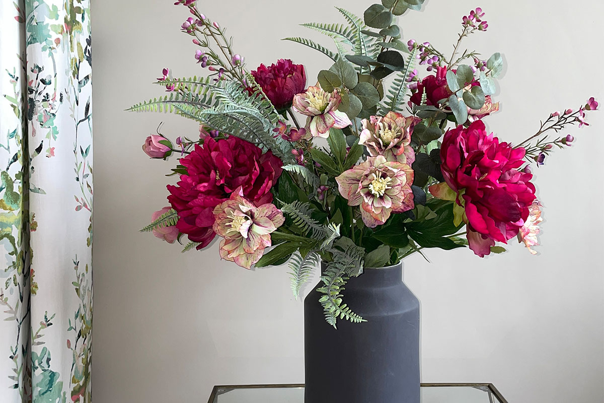 faux pink flower arrangement in black churn vase